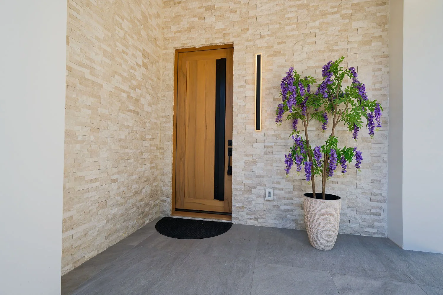 Completed project — 2: Stone-clad entry with a wood door and flowering plant