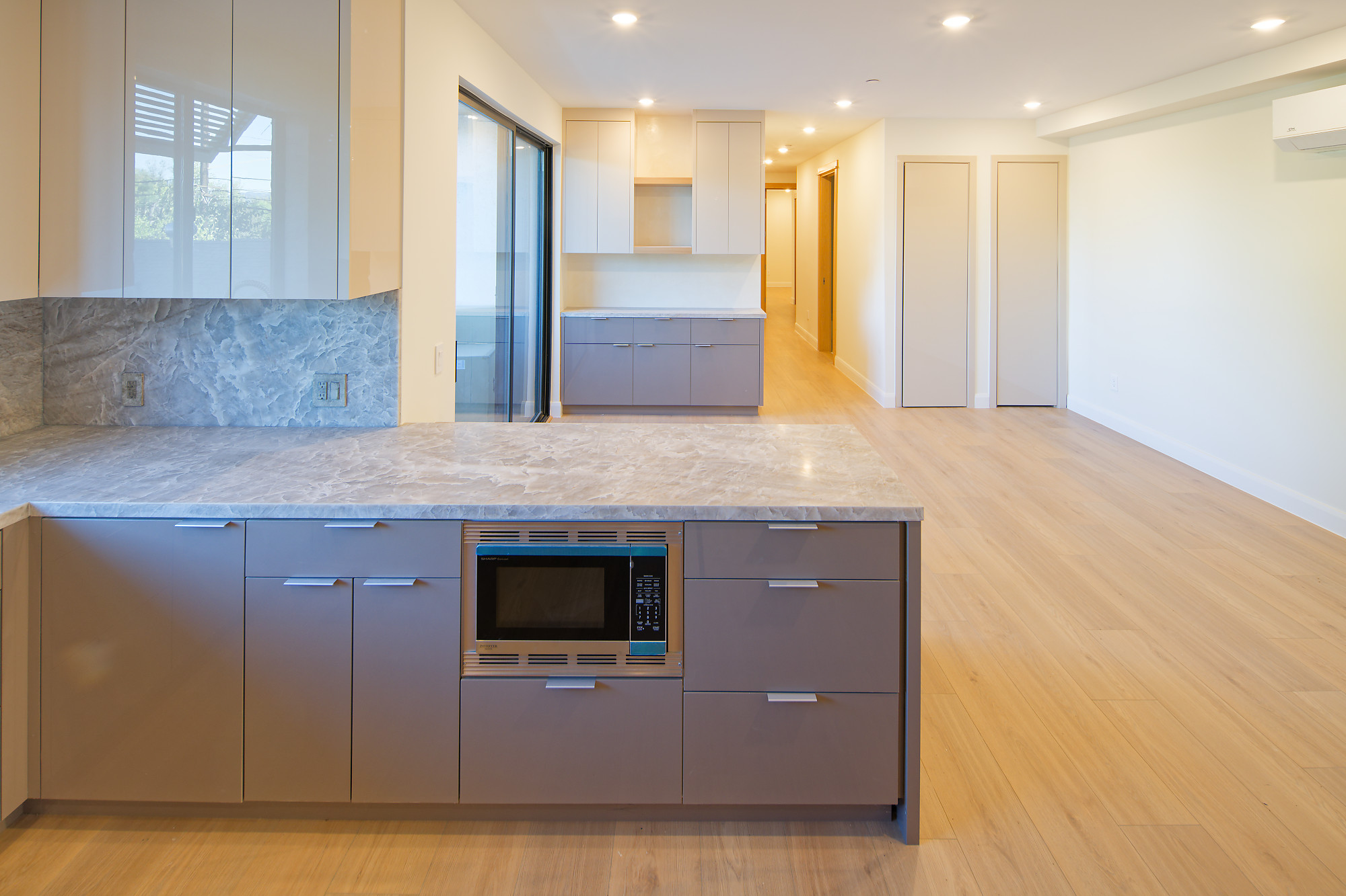 Completed project — 4: Kitchen peninsula with stone countertop, built-in microwave, and open living space