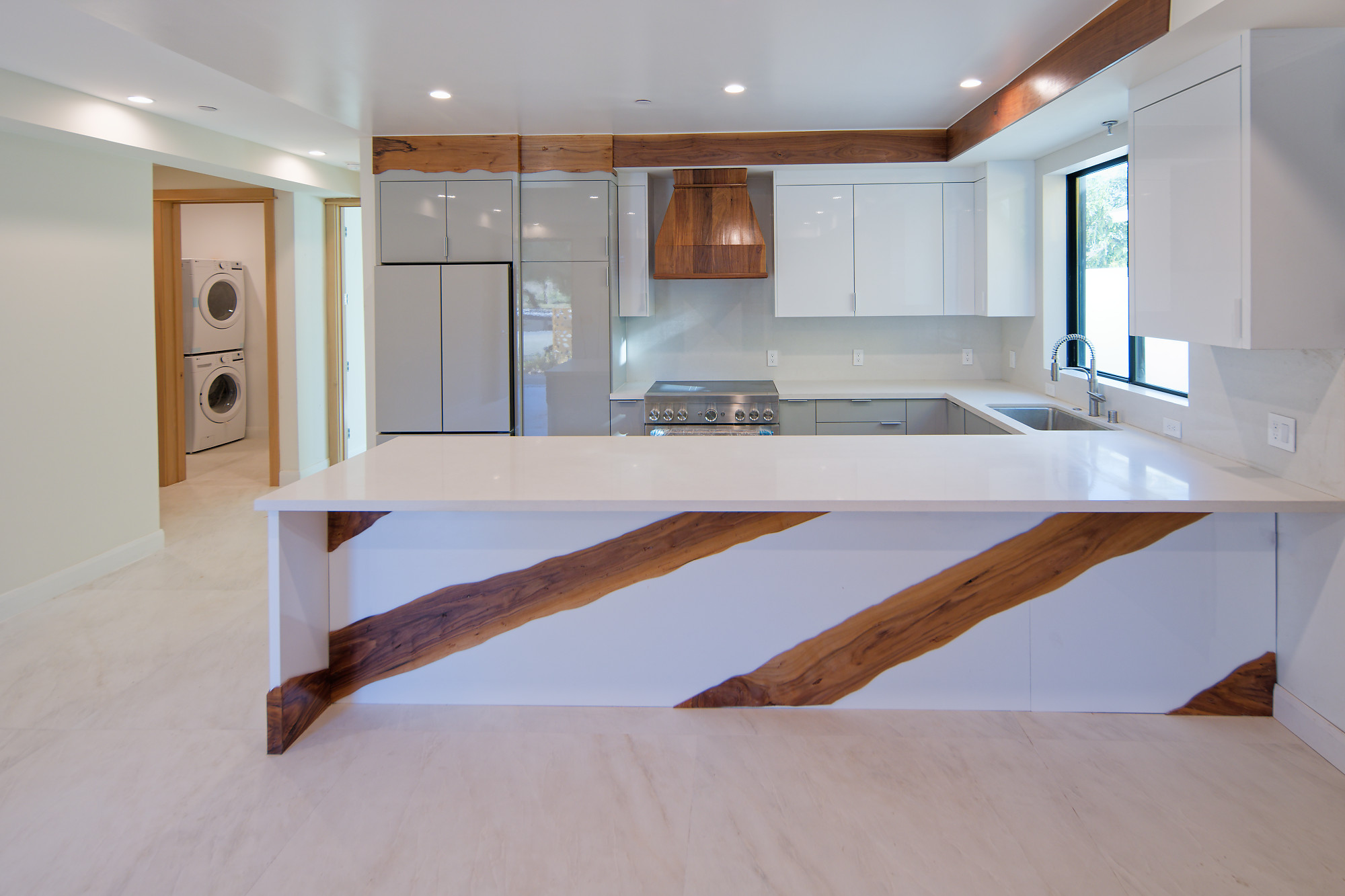Completed project — 16: White kitchen with wood accents, a wood range hood, and a peninsula